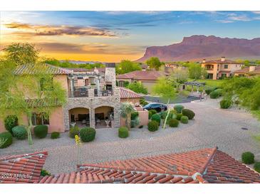 Charming home with stone accents, a private balcony, well manicured landscaping and mountain views at sunset at 7751 E Golden Eagle Cir, Gold Canyon, AZ 85118