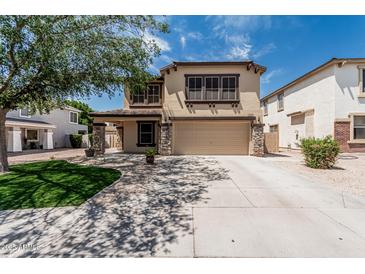 Two-story home with a two-car garage, desert landscaping, and tan exterior paint at 10440 E Osage Ave, Mesa, AZ 85212