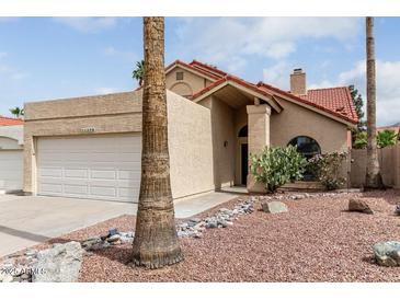 Charming single-story home featuring a red tile roof, desert landscaping, and an attached two-car garage at 11290 E Poinsettia Dr, Scottsdale, AZ 85259