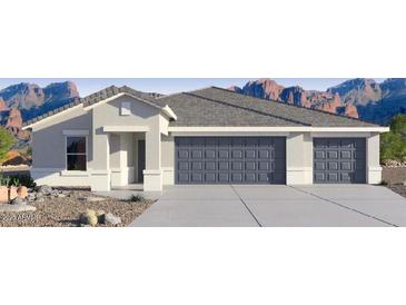 Charming single-story home with a three-car garage and desert landscaping against a backdrop of majestic mountains at 12235 E Agave Ln, Florence, AZ 85132