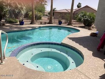 Inviting pool and spa with blue tile accents surrounded by a desert landscaped backyard at 15753 W Kino Dr, Surprise, AZ 85374