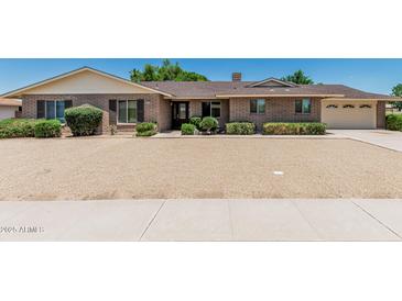 Charming brick home featuring a well-manicured gravel yard and a convenient two-car garage at 4402 W El Caminito Dr, Glendale, AZ 85302