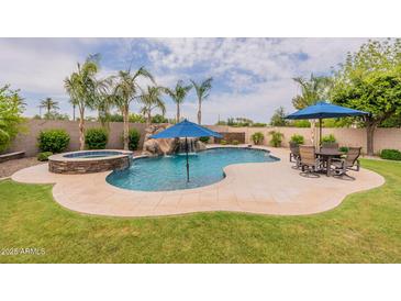 Inviting pool area featuring a rock waterfall, spa, and outdoor seating perfect for relaxing and entertaining at 550 W Powell Way, Chandler, AZ 85248