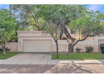 Charming home exterior featuring a two-car garage and beautiful mature trees in a well-maintained front yard at 6002 N 5Th Pl, Phoenix, AZ 85012