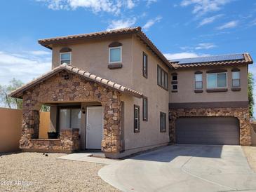 Two-story home featuring a stone accented entry and garage with solar panels at 6620 W Shaw Butte Dr, Glendale, AZ 85304