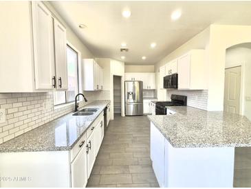 Modern kitchen with stainless steel appliances, granite countertops, and white cabinets offers a clean, stylish design at 7116 W Sophie Ln, Laveen, AZ 85339