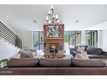 Bright living room featuring a striking brick fireplace, modern chandelier, and stylish furniture at 733 W El Camino Dr, Phoenix, AZ 85021
