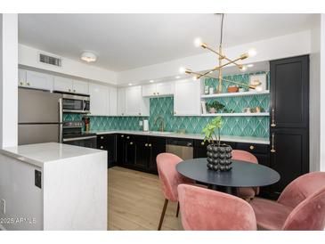 A stylish kitchen with black and white cabinets, modern lighting, and a unique geometric backsplash at 1225 E Medlock Dr # 206, Phoenix, AZ 85014