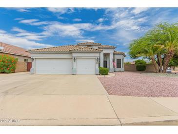 Charming single-story home boasts a three-car garage, tile roof, and neat landscaping at 13368 W Rimrock St, Surprise, AZ 85374
