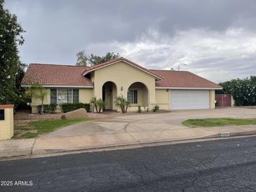 Charming single-story home featuring an arched entryway, desert landscaping, and a spacious two-car garage at 4801 E Sheena Dr, Scottsdale, AZ 85254