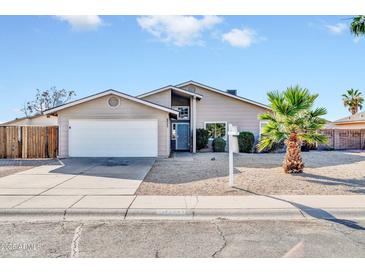 Charming single-story home featuring a two-car garage and a well-maintained, low-maintenance yard with a young palm tree at 11044 N 75Th Dr, Peoria, AZ 85345