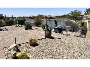 Beautiful backyard with a lake view, desert landscaping, and a firepit with seating, perfect for outdoor entertaining at 16858 S 180Th Ave, Goodyear, AZ 85338