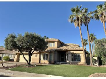 Charming tan two-story home with tile roof, palm trees, manicured lawn, and desert landscaping at 2549 E Desert Trumpet Rd, Phoenix, AZ 85048
