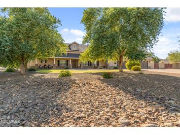 Spacious home featuring desert landscaping, a stone-lined drainage path, and mature trees at 1409 E Dove Pl, Casa Grande, AZ 85122