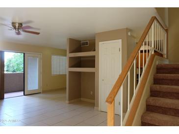 Bright living room featuring tile floors, a ceiling fan, sliding glass doors to the outside, and staircase at 151 E Broadway Rd # 210, Tempe, AZ 85282