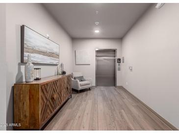 Hallway with art and a wood cabinet leads to an elevator with wood floors at 2511 W Queen Creek Rd # 174, Chandler, AZ 85248