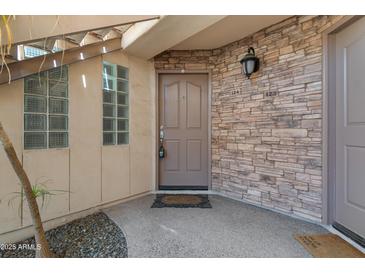 Condo front entrance with stone wall accent and covered entry at 3235 E Camelback Rd # 124, Phoenix, AZ 85018