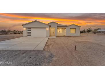 Stunning single-story home boasting a modern design and a large garage under a vibrant sunset sky at 28834 N 175Th Ave, Surprise, AZ 85387