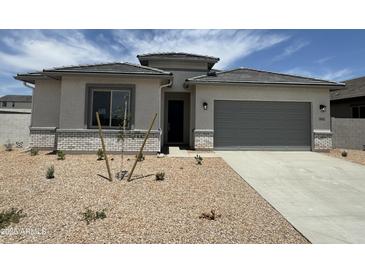 Charming single-story home with a gray garage door, desert landscaping, and a tiled roof at 6952 E Brushy Bill Rd, San Tan Valley, AZ 85143
