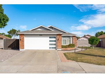 Charming single-story home with a well-maintained lawn, brick accents, and a modern garage door at 8828 E Des Moines St, Mesa, AZ 85207