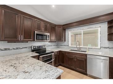 Beautiful kitchen with stainless steel appliances, granite countertops, and dark wood cabinetry at 908 W Mohawk Ln, Phoenix, AZ 85027