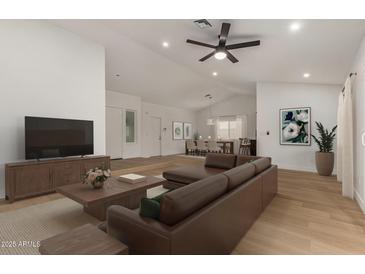 Bright living room featuring a brown sectional sofa, wood floors, and an open concept dining area at 908 W Mohawk Ln, Phoenix, AZ 85027
