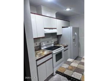 Galley kitchen featuring white cabinetry, black and brown countertops, and white appliances at 8055 E Thomas Rd # H103, Scottsdale, AZ 85251