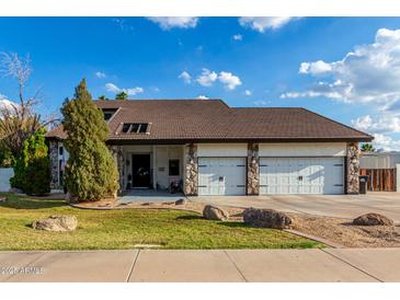 Charming home featuring stone accents, a three-car garage, and a well-maintained front yard at 2149 E Hermosa Vista Dr, Mesa, AZ 85213