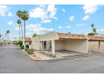 Inviting single-story home featuring a carport, desert landscaping, and a charming facade with palm trees in the front yard at 5224 S Monaco Dr, Tempe, AZ 85283