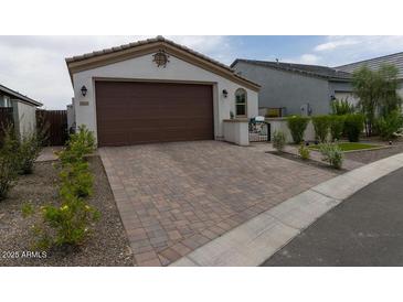 Charming single-Gathering home showcasing a brown garage door and brick paver driveway, surrounded by well-maintained landscaping at 5633 N 206Th Ave, Buckeye, AZ 85396