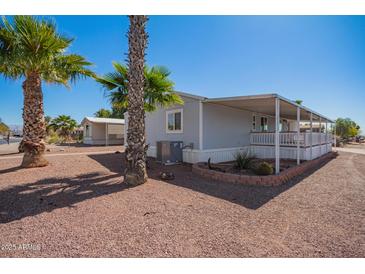 Charming home with a covered porch, desert landscaping, and mature palm trees at 8823 E Billings St, Mesa, AZ 85207