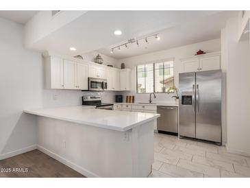 Bright kitchen features stainless steel appliances, white cabinets, subway tile backsplash, and a spacious quartz countertop island at 2315 N 52Nd St # 144, Phoenix, AZ 85008