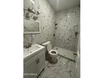 Well-lit bathroom featuring marble tile, vanity with white cabinets, and updated shower at 4049 N 81St Ave, Phoenix, AZ 85033