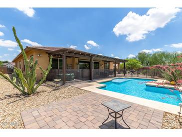 Backyard pool area with desert landscaping, shaded patio, and privacy fence, creating a relaxing outdoor space at 13720 N 148Th Dr, Surprise, AZ 85379
