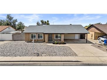 Charming brick home featuring a covered carport, low maintenance yard, and inviting curb appeal at 2435 E Harmony Ave, Mesa, AZ 85204