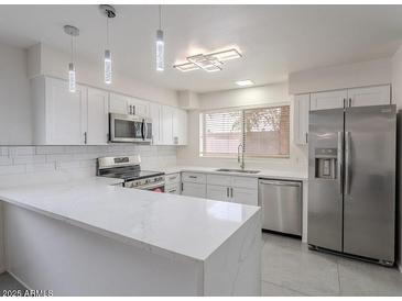 Stylish kitchen featuring stainless steel appliances, a breakfast bar, and elegant lighting fixtures at 5817 S Siesta Ln, Tempe, AZ 85283