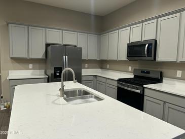 Modern kitchen features stainless steel appliances, gray cabinets, and a white quartz countertop island at 40816 W Sunland Dr, Maricopa, AZ 85138