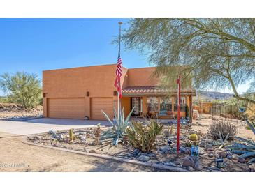 Inviting Southwestern-style home with a desert landscape, an American flag, and a three-car garage at 44421 N 12Th St, New River, AZ 85087