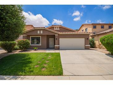 Inviting single-story home showcases a vibrant lawn, desert landscaping, and classic Southwestern architecture with a tile roof at 45309 W Gavilan Dr, Maricopa, AZ 85139