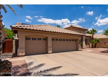 Spacious three-car garage with tan exterior, tile roof, and ample parking space on a sunny day at 1884 E Stephens Dr, Tempe, AZ 85283