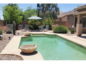 Relaxing backyard pool with lounge chairs, desert landscaping, and striped umbrella at 2894 N Paisley Ave, Casa Grande, AZ 85122