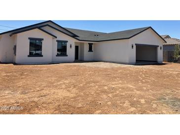 New construction features a white stucco exterior, dark grey trim, and a spacious two-car garage at 5499 E Red Bird Ln, San Tan Valley, AZ 85140