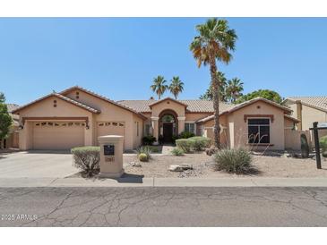 Inviting single-story home with desert landscaping, palm trees, and a charming tile roof at 12183 E Mercer Ln, Scottsdale, AZ 85259