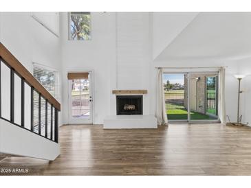 Bright living room with fireplace, wood-look flooring, and high ceilings at 18206 N 45Th Ave, Glendale, AZ 85308