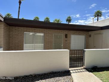 Charming single-story home with a brick facade, white fencing, and well-maintained landscaping at 220 S Old Litchfield Rd # 104, Litchfield Park, AZ 85340