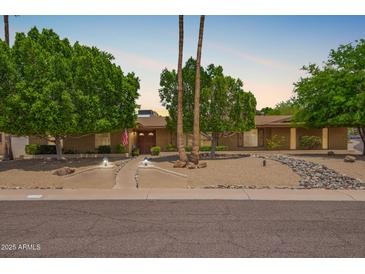 Charming single-story home featuring desert landscaping, mature trees, and a welcoming entrance at 2234 E Lawrence Rd, Phoenix, AZ 85016