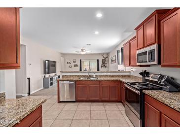 Well-lit kitchen featuring granite countertops, stainless steel appliances, and rich wood cabinetry at 25447 W Heathermoor Dr, Buckeye, AZ 85326