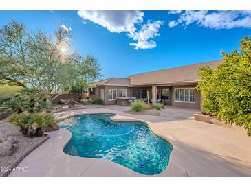 Inviting backyard oasis featuring a freeform pool, mature trees, and ample patio space for outdoor entertaining at 5077 E Lonesome Trl, Cave Creek, AZ 85331