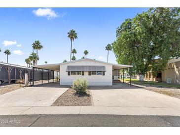 Charming single-story home with covered parking and a well-maintained front yard with lush green trees at 9501 E Broadway Rd # Ofc, Mesa, AZ 85208