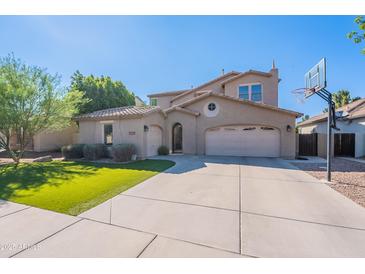 Inviting two-story home featuring a well-manicured lawn, three-car garage, and basketball hoop in the driveway at 1128 E Phelps St, Gilbert, AZ 85295